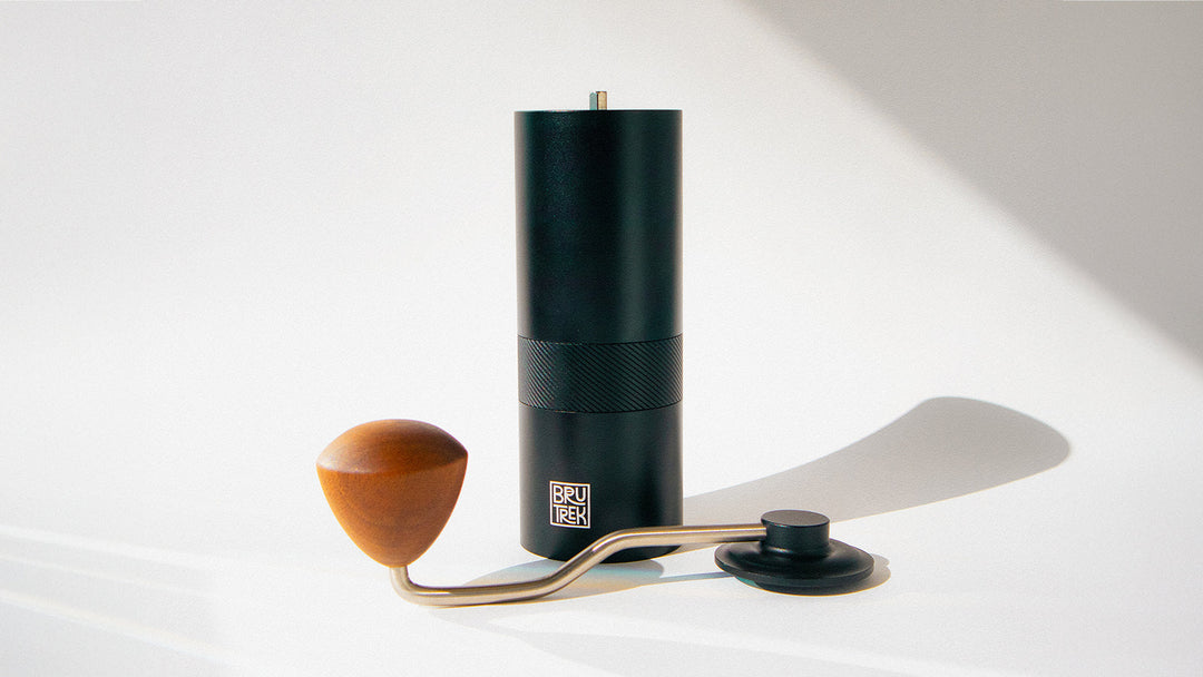 A partially disassembled hand coffee grinder on a white background.
