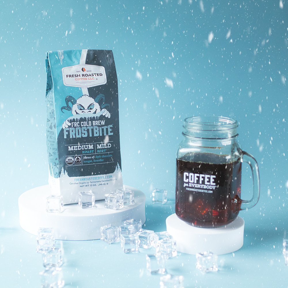Fresh Roasted Coffee Frostbite Cold Brew bag with iced coffee glass, medium roast flavor in a winter-themed setup.